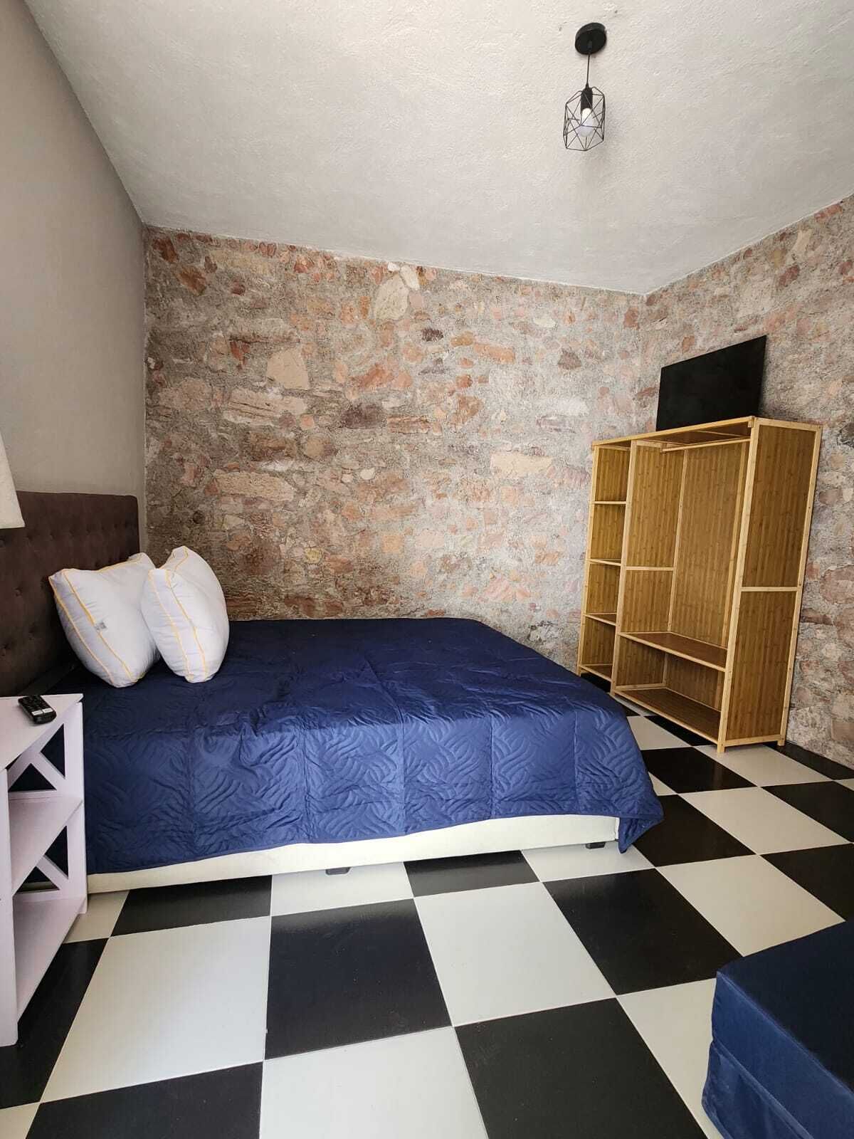 Una habitación con cama, armario y piso de cuadros.