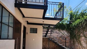A building with a balcony, a staircase, and a paved courtyard.