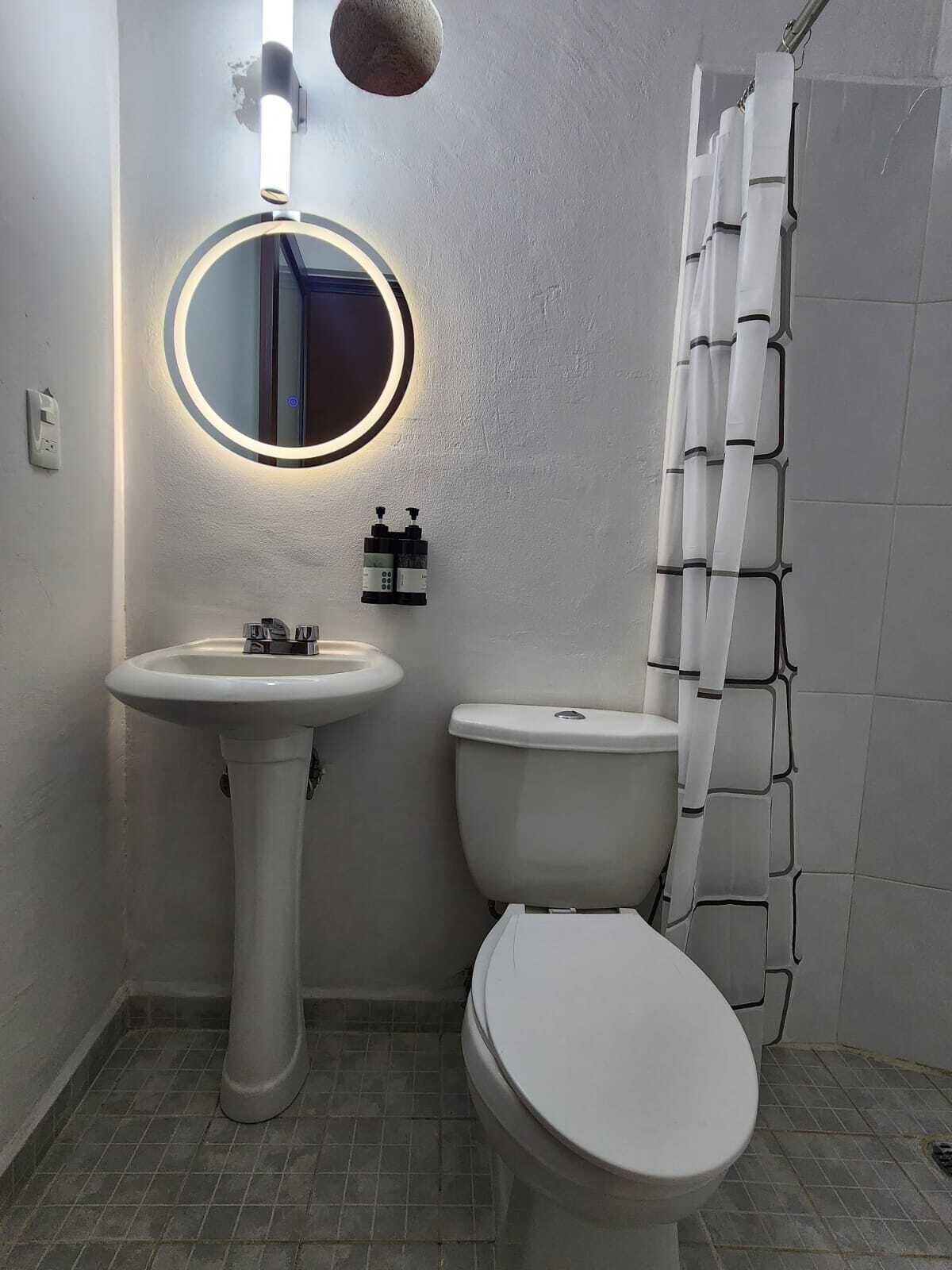 A bathroom with a pedestal sink, toilet, and a shower curtain.
