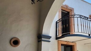A building with a balcony, a door, and a light fixture.