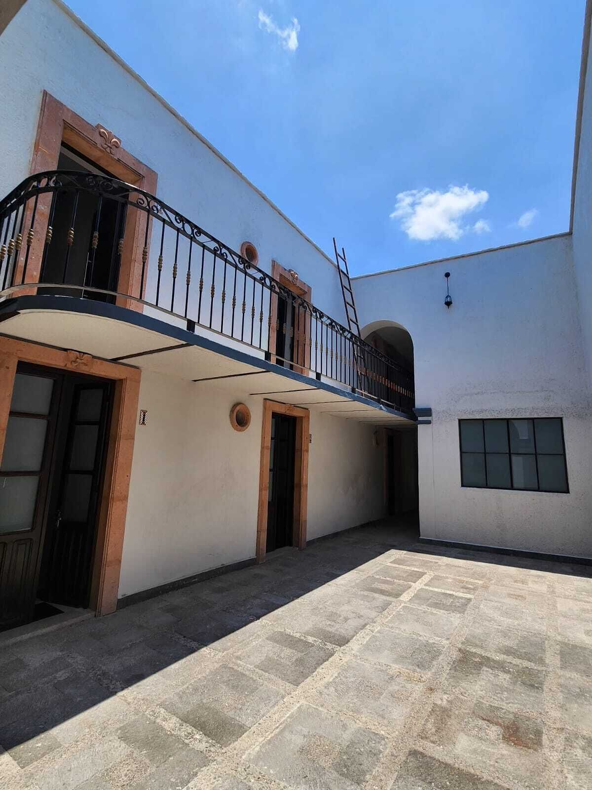 Un edificio con un cortile interno, un balcone con ringhiere in metallo e un portone con finestra.
