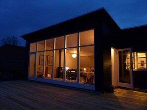 A modern building with large windows, a deck, and a visible interior with furniture. - 4 Star Holiday Home in Allinge (Allinge)