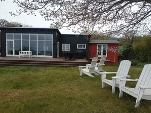 A modern house with a deck, outdoor seating, and a red shed. - 4 Star Holiday Home in Allinge (Allinge)
