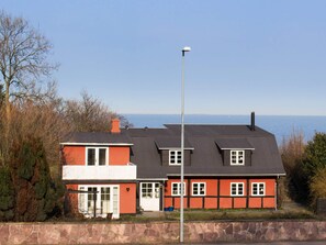 A two-story house with a stone wall in front, a clear view of the sea, and a street lamp. - 4 Star Holiday Home in Allinge (Allinge)