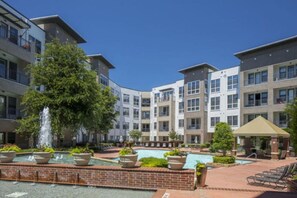 A courtyard with a swimming pool, lounge chairs, and a fountain. - Stylish Modern Studio | KING & FULL BED + Pool&Gym (Irving)