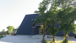 Ein modernes Gebäude mit geneigtem Dach, einer Treppe, die zum Eingang führt, und einer Schotterzufahrt.