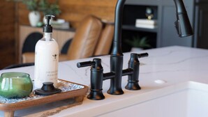 Eine Küche mit weißer Arbeitsplatte, einem schwarzen Wasserhahn und einer Flasche Kokos-Händeseife.