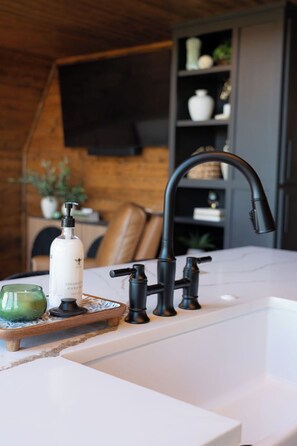 A kitchen with a white countertop, a black faucet, and a bottle of coconut hand soap. - Minutes to Rocker B Ranch and PK Lake,  Secluded Ridgeline Retreat. (Graford)