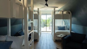 Ein Zimmer mit Etagenbetten, einem Schreibtisch und Blick ins Freie.