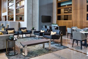 Eine moderne Lobby mit Sofas, Sesseln, einem Couchtisch und einem Fernseher.