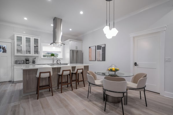 Une cuisine moderne dotée d’un îlot central, de tabourets de bar et d’une table à manger avec des chaises.