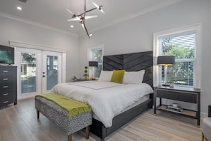 A bedroom with a bed, bedside tables, a bench, a TV, and a window with blinds. - 3 Bedroom unit in American Beach,
Fernandina 
5 minutes walk away from the beach (Fernandina Beach)