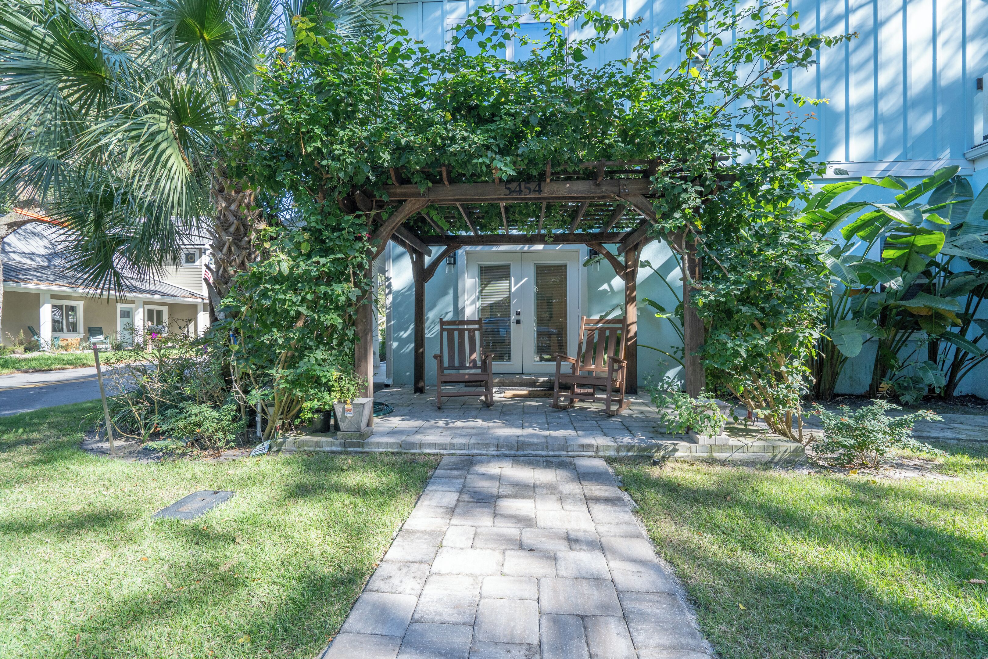 A covered patio with a wooden pergola, a stone pathway, and a bench.