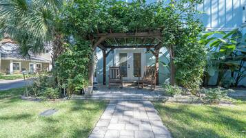 A covered patio with a wooden pergola, a stone pathway, and a bench.