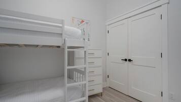 A room with a bunk bed, a dresser with drawers, and a set of double doors.