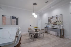 A modern dining area with a round table, chairs, a hanging light fixture, and artwork on the walls. - 3 Bedroom unit in American Beach,
Fernandina 
5 minutes walk away from the beach (Fernandina Beach)