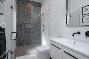 A modern bathroom with a glass shower enclosure, a white sink, and a marble wall. - 3 Bedroom unit in American Beach,
Fernandina 
5 minutes walk away from the beach (Fernandina Beach)