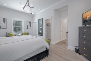 Une chambre à coucher avec un lit, une commode, un téléviseur et un placard.