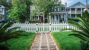 A residential street with a white picket fence, a stone pathway, and houses with front porches. - Downtown Savannah * 2 Bedroom * Firepit * Dogs OK * Private Patio (Savannah)