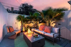 A patio with a sofa, a chair, a fire pit, and potted plants. - Downtown Savannah * 2 Bedroom * Firepit * Dogs OK * Private Patio (Savannah)