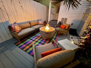 Une terrasse avec une table ronde, deux canapés et un tapis aux couleurs vives.