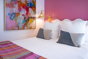 A bed with white bedding, a colorful striped blanket, and a large abstract painting on the wall. - Savannah Home * Firepit * Dogs OK * Free Parking (Savannah)