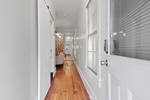 Un couloir doté d’un plancher en bois, de murs blancs et d’une porte avec une fenêtre.