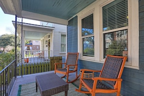 A porch with two rocking chairs and a small table, a wooden fence, and a house in the background. - Savanah Home, Walkable Downtown, 30+ Days (Savannah)