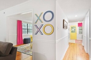 A hallway with a white wall, a yellow door, and a pink curtain.