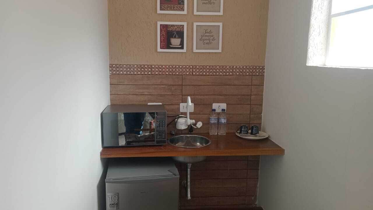 A compact kitchenette with a coffee machine, a small sink, and a refrigerator.