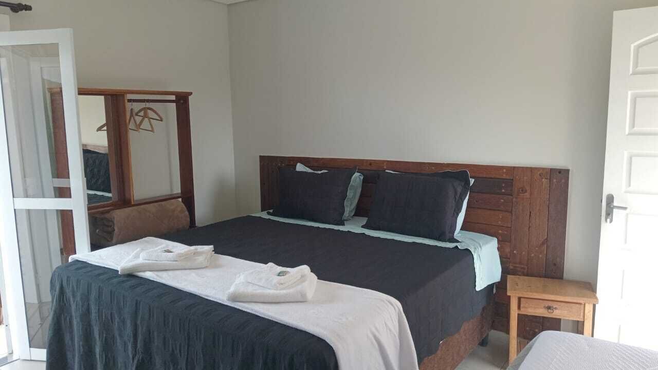 A bedroom with a bed, a wooden headboard, a nightstand, and a mirror.