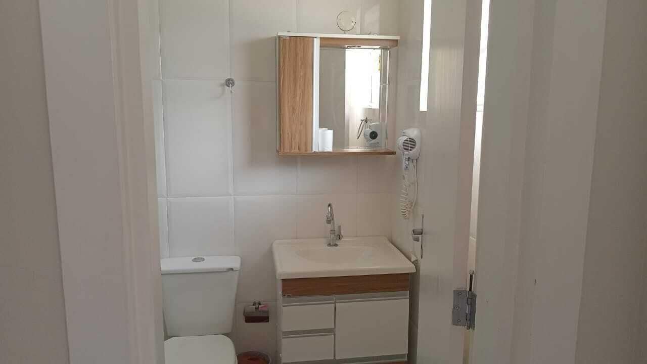 Un baño con inodoro, lavamanos, espejo y secador de pelo.