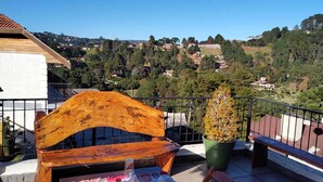 Un conjunto de banco y mesa de madera en un balcón con vistas a un paisaje montañoso.