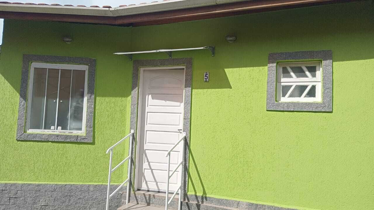 Ein Gebäude mit grüner Fassade, einer weißen Tür und zwei Fenstern mit weißen Rahmen.