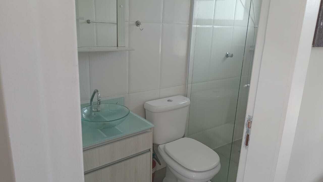 Ein Badezimmer mit Duschkabine aus Glas, Toilette in Weiß und Waschbecken mit Glasablage.