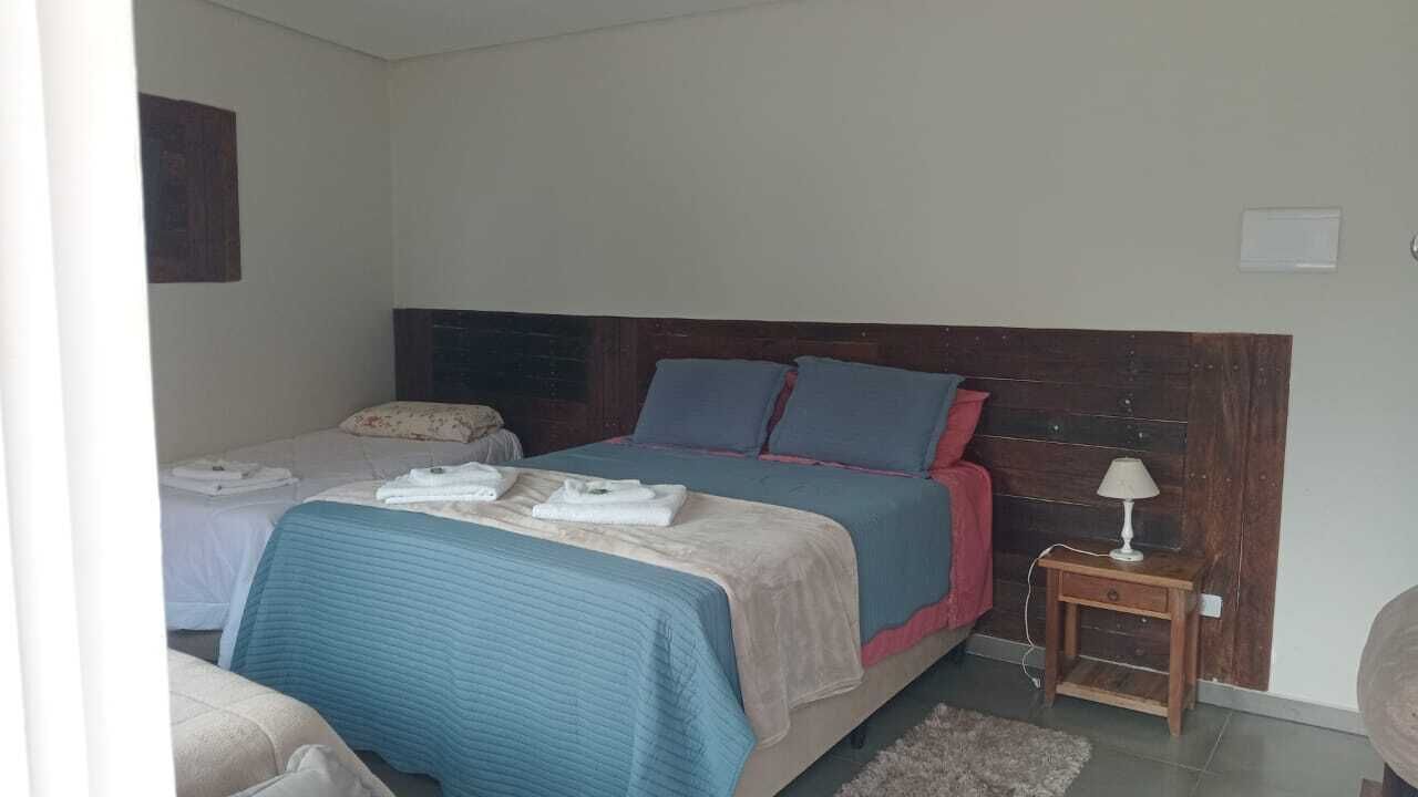 Un dormitorio con dos camas, una mesita de noche con lámpara y una alfombra pequeña.