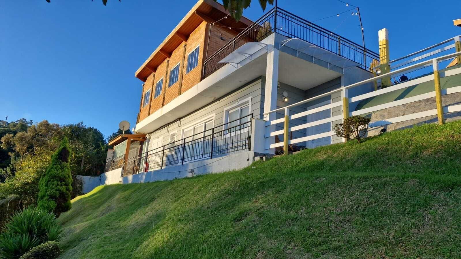 A two-story building with a balcony, a garage, and a grassy slope.