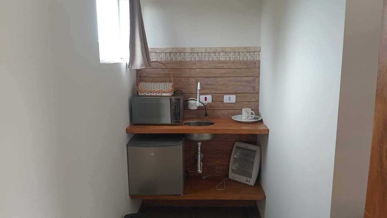 Eine kompakte Küchenzeile mit Mikrowelle, kleinem Kühlschrank, Spüle und Ventilator.