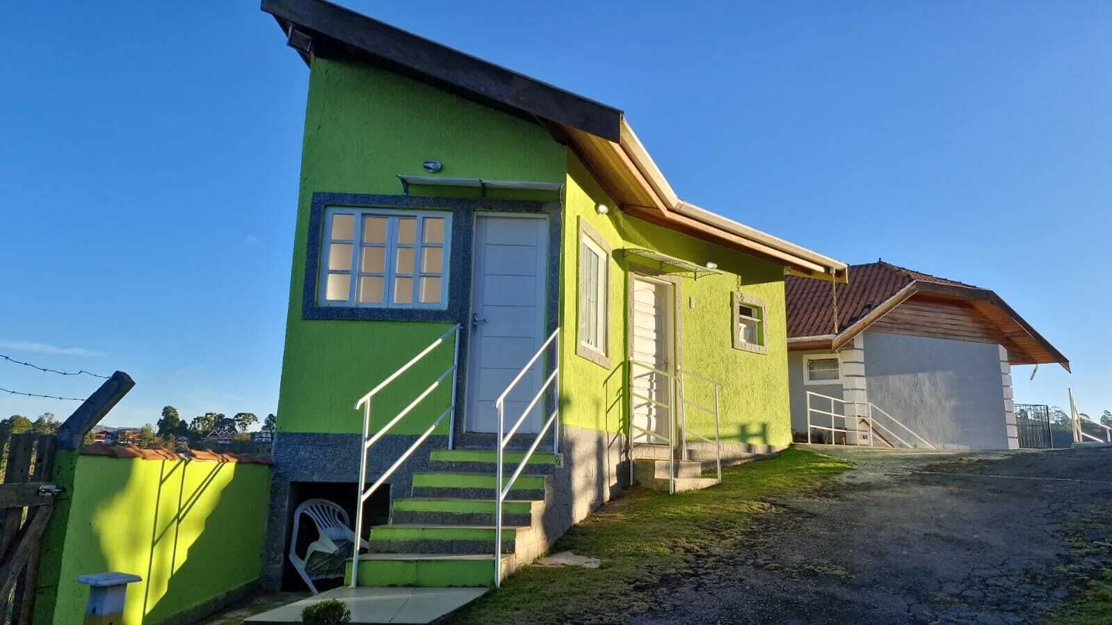 Una casa de dos pisos con fachada verde, una puerta principal y una escalera que conduce al segundo piso.
