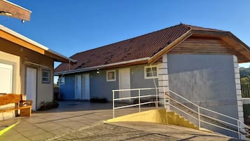 Un edificio con tejado de tejas, una escalera y un banco.