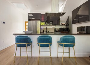 Une cuisine moderne dotée d’un îlot central, de tabourets de bar et d’un four à micro-ondes.