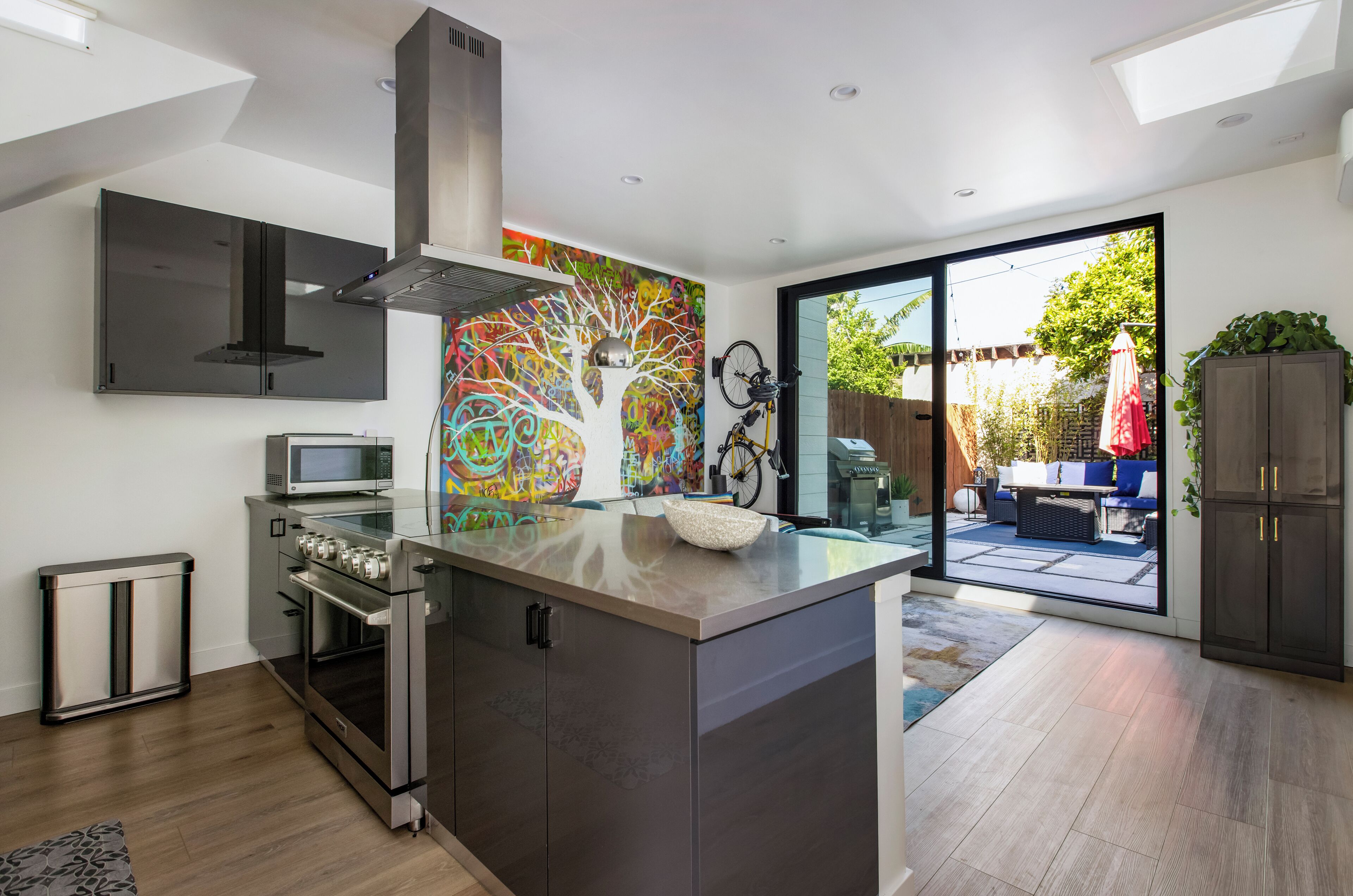 A modern kitchen with a large island, built-in oven, and a colorful mural.