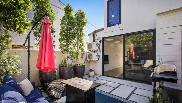 Eine Terrasse mit Gartenmöbeln, einem Grill und Kübelpflanzen.