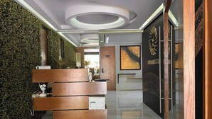 A reception area with a wooden desk, a green wall, and a modern ceiling design. - Ocean-View King Studio with Private Balcony & Rooftop Pool (Playa del Carmen)