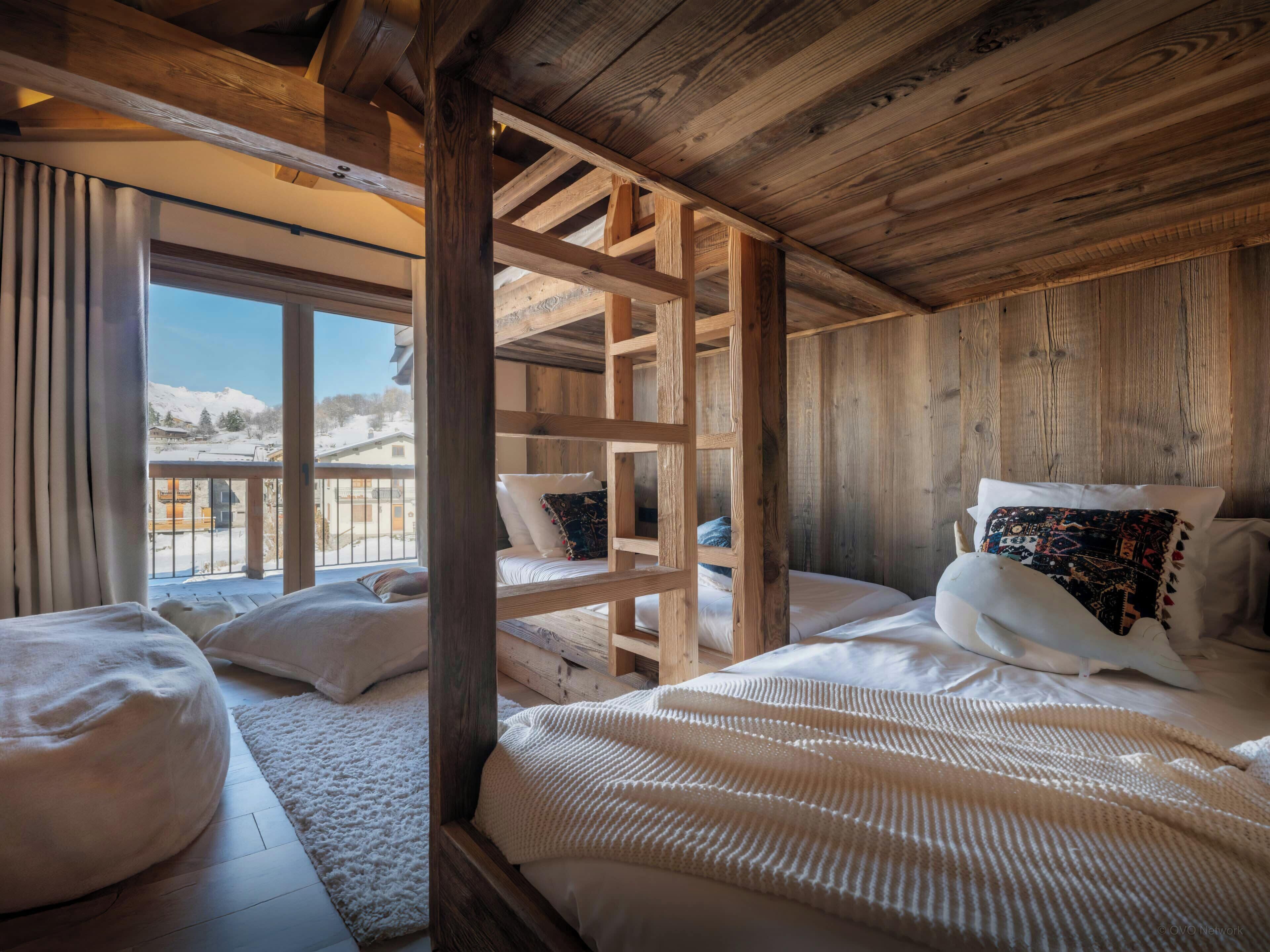 Habitación de cabaña de madera con una cama, una ventana y vistas a un paisaje nevado.