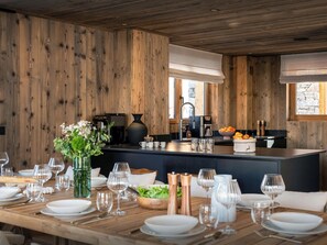 A modern kitchen with wooden walls, a central island, and a dining area set for six.