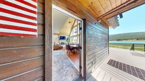 Uma cabana de madeira com área de refeições, sala de estar e vista para um lago.
