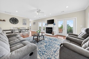 A spacious living room with a fireplace, comfortable seating, and a large clock on the wall. - Winyah Bay House | Historic Georgetown Waterfront (Georgetown)