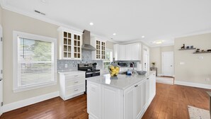 A kitchen with white cabinets, a central island, and a window with blinds.