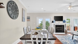 A dining room with a large wall clock, a fireplace, and a TV.